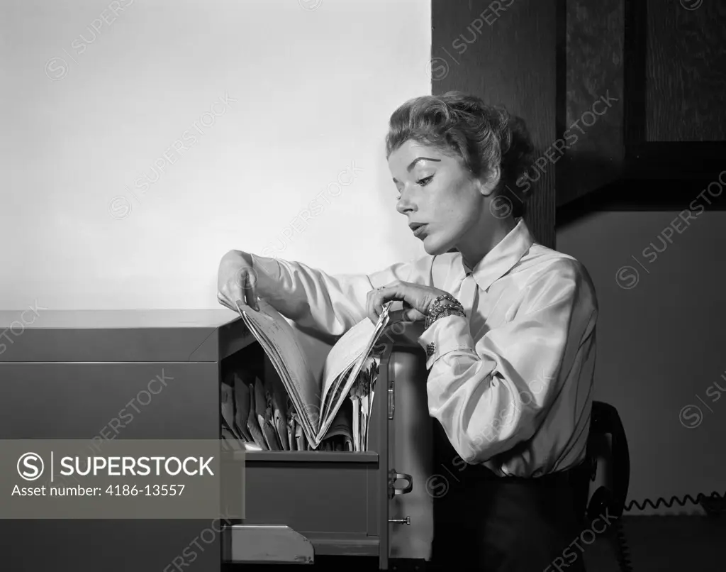 1950S Woman Working In Office Looking Through Files In File Cabinet