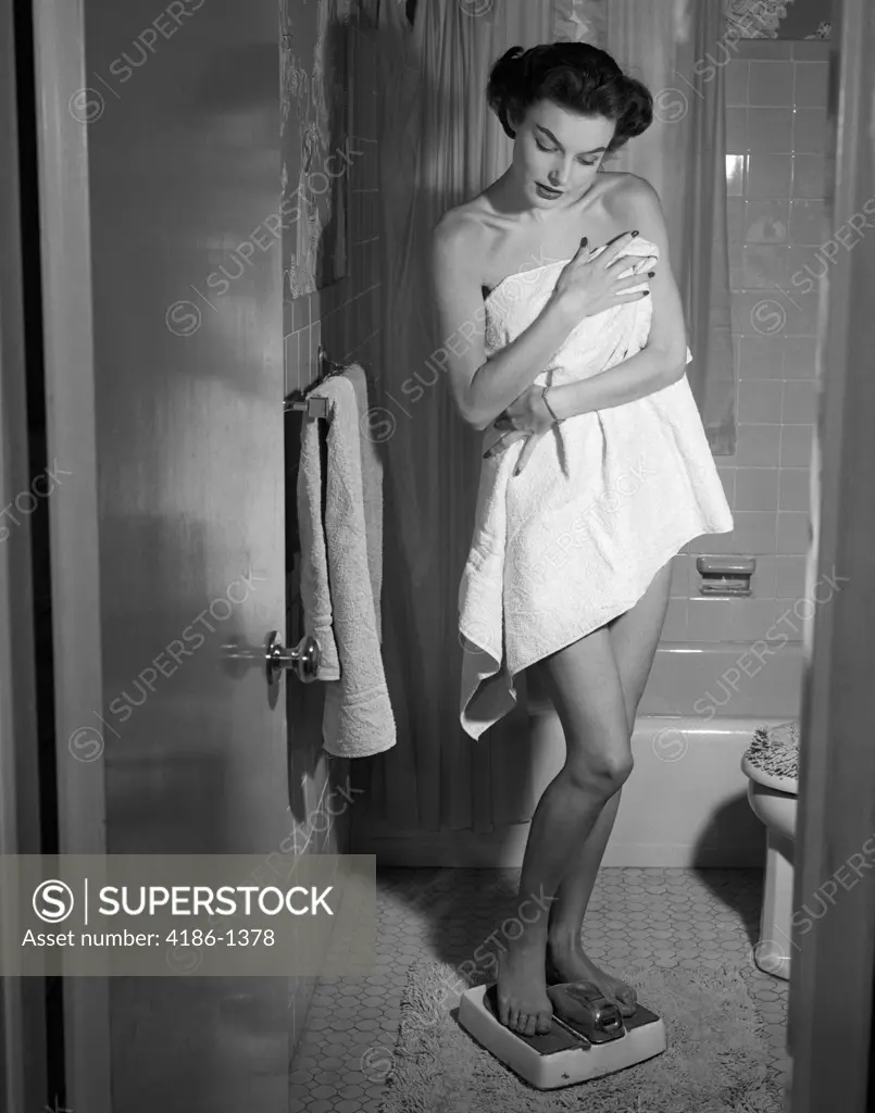 1950S Woman Wrapped In Towel Stepping On Bathroom Scale