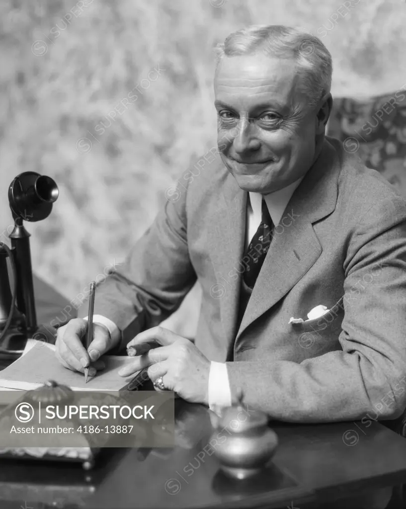 1920S 1930S Smiling Man Businessman Salesman Sitting At Desk Smoking Cigar Writing A Memo