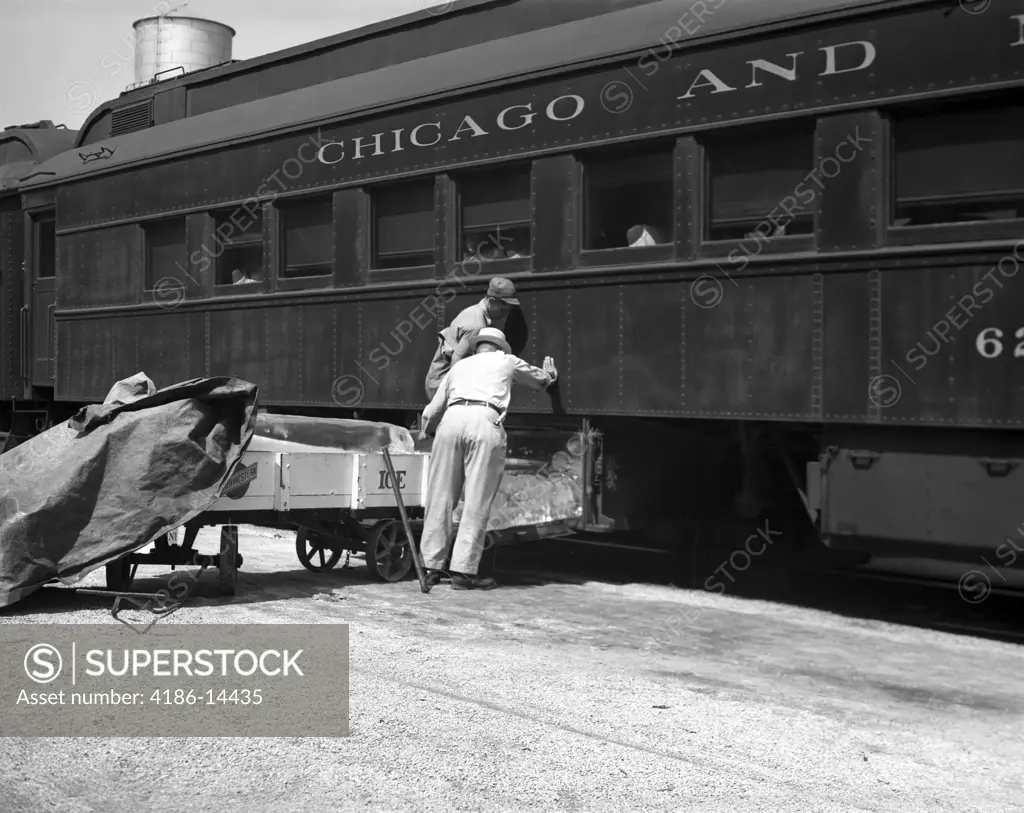 1930S 1940S Two Railroad Workers Putting Cakes Of Ice Into Climate Control Air Conditioning Compartments Of Passenger Railroad Train