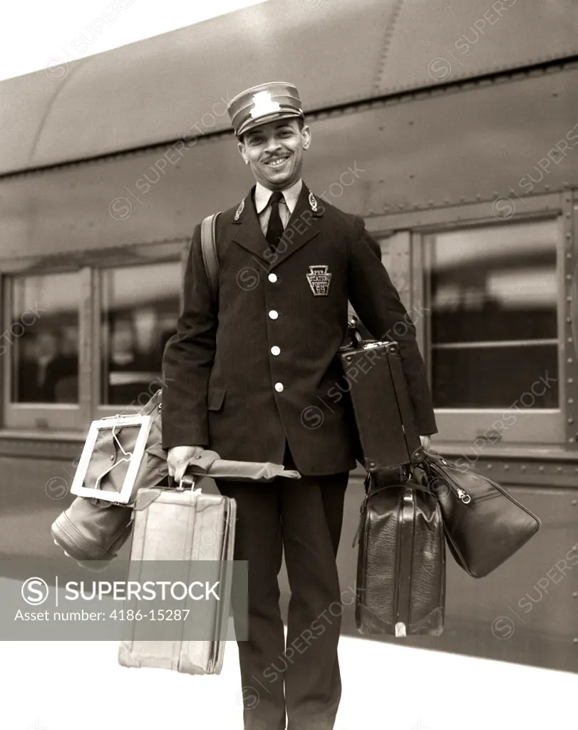 1930S 1940S Portrait Smiling African American Man Red Cap Porter Carrying Luggage Bags Suitcases Passenger Railroad Train