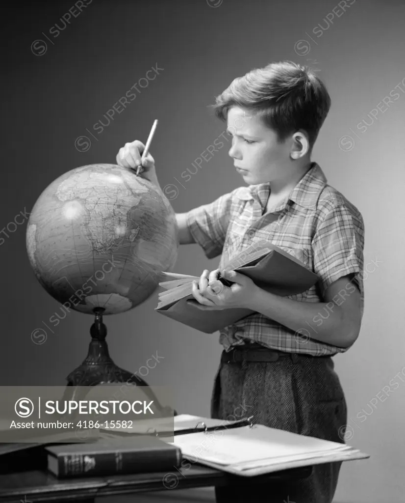 1940S 1950S Serious Boy Finding Location On World Earth Globe With Pencil Hold Open Book Geography