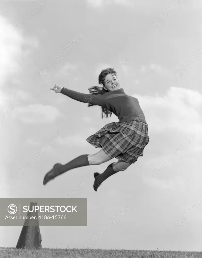 1960S Cheerleader In Sweater Plaid Skirt & Knee Socks Leaping High In Air