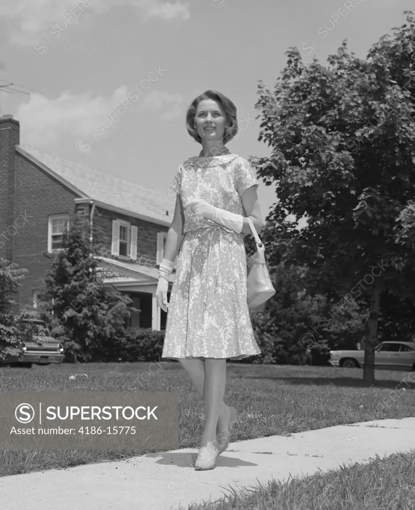 1960S Woman Wearing Print Dress Holding Handbag Walking Down Suburban Street