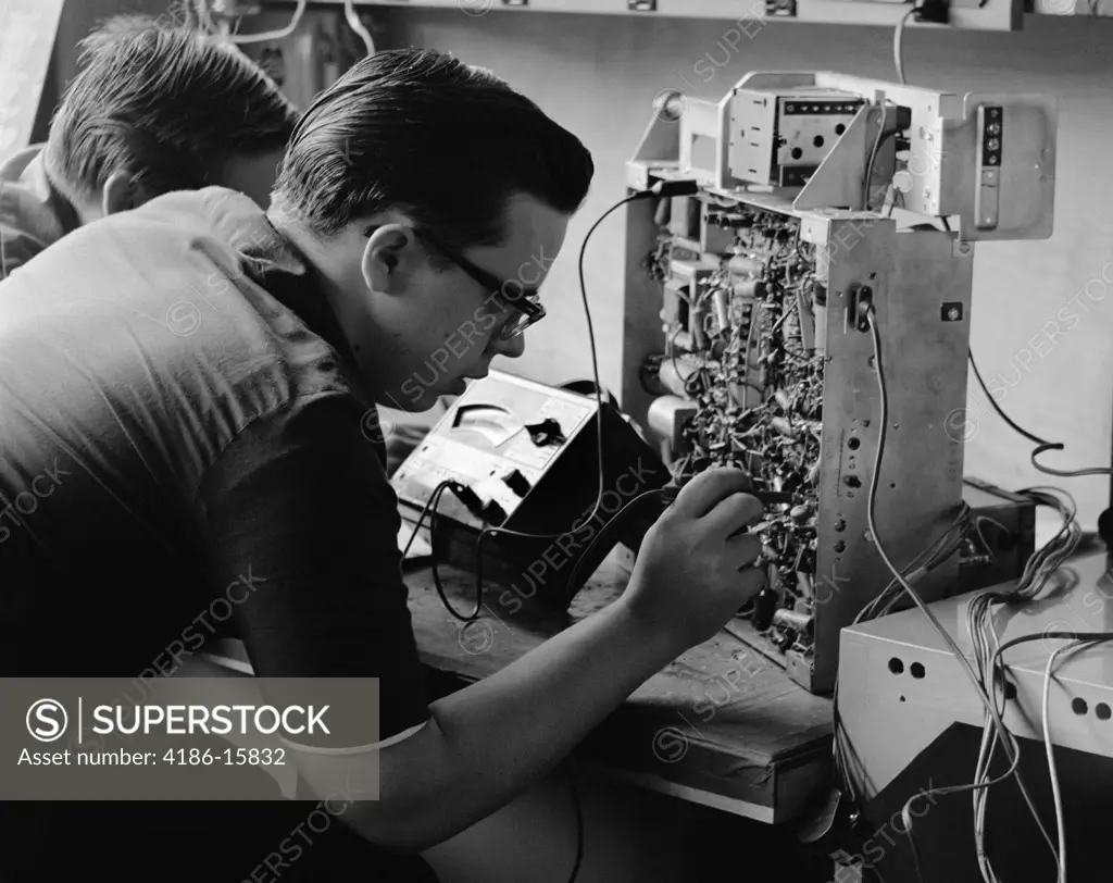 1960S Side View Of Students Working On Circuitry Panel With Small Soldering Iron