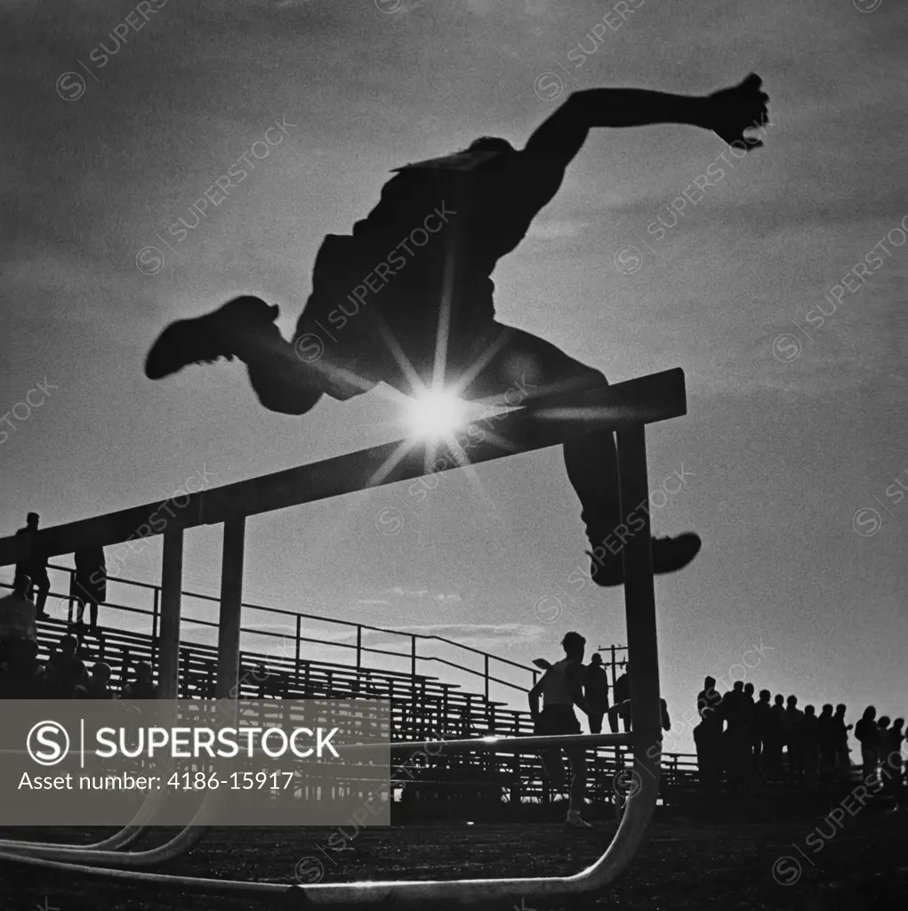 1970S Sun Rays Through Silhouette Of Man Jumping Track Field Hurdle