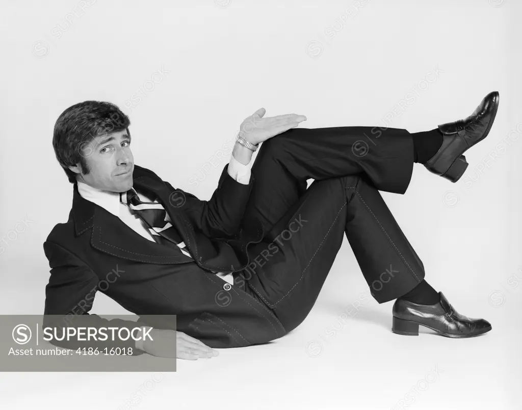 1970S Business Man Lying On Side Making Gesture With Hand