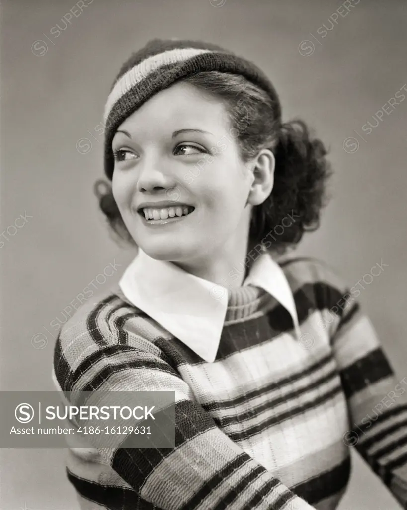 1930s SMILING BRUNETTE WOMAN LOOKING BACK OVER HER SHOULDER WEARING STRIPED KNIT SWEATER WHITE COLLAR AND STRIPED KNIT CAP