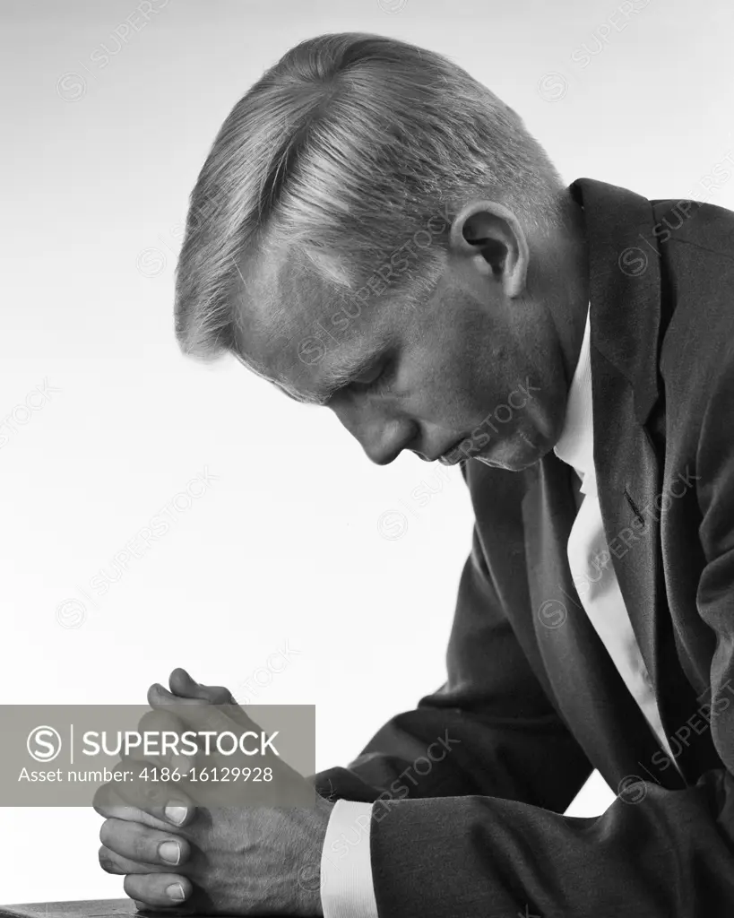 1960s RELIGIOUS BLOND MAN WEARING COAT AND TIE KNEELING HEAD BOWED HANDS CLASPED IN PRAYER