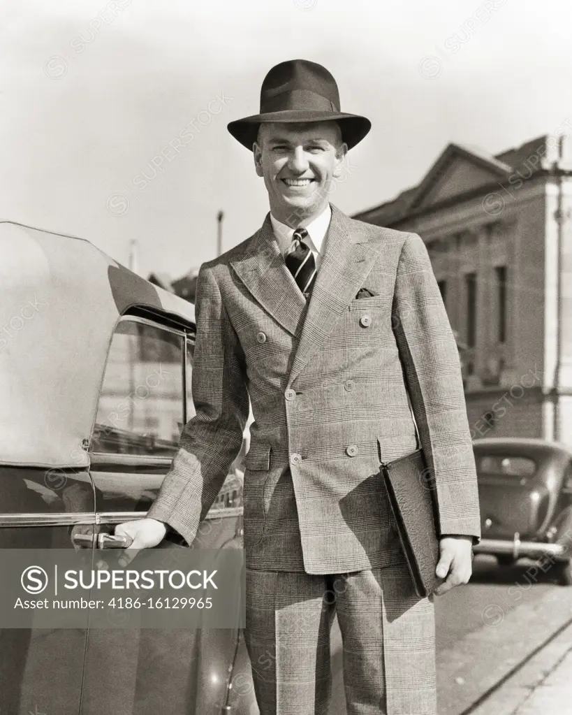 1940s SMILING TRAVELING SALESMAN LOOKING AT CAMERA WEARING DOUBLE BREASTED SUIT HAND ON HANDLE TO OPEN CONVERTIBLE CAR DOOR