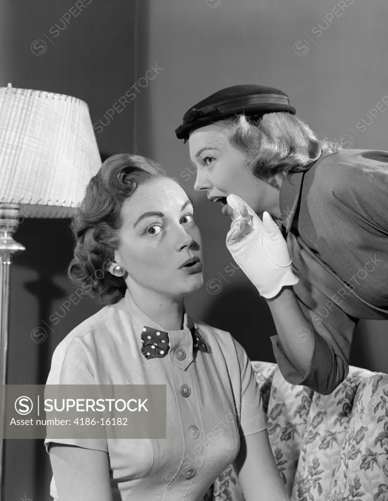 1950S Woman In Hat & White Gloves Leaning Down To Whisper Gossip To Friend