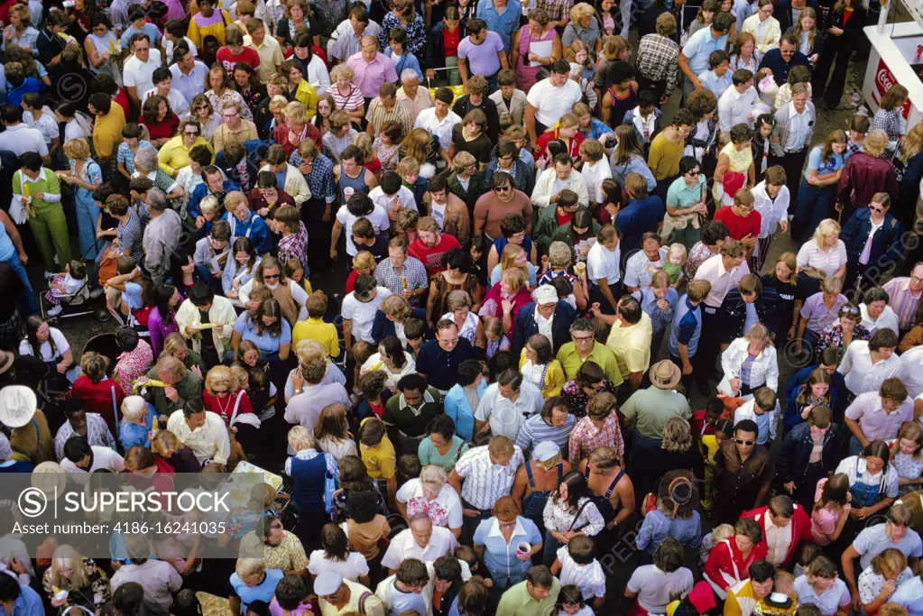 1970s OVERHEAD AERIAL VIEW OF OUTDOOR CROWD OF CASUALLY DRESSED PEOPLE MEN WOMEN TEENAGERS AND CHILDREN