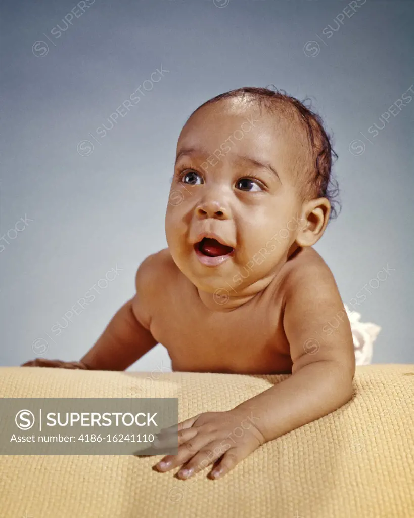 1960s ENERGETIC SMILING AFRICAN-AMERICAN BABY BOY CRAWLING ON COTTON SUMMER BLANKET