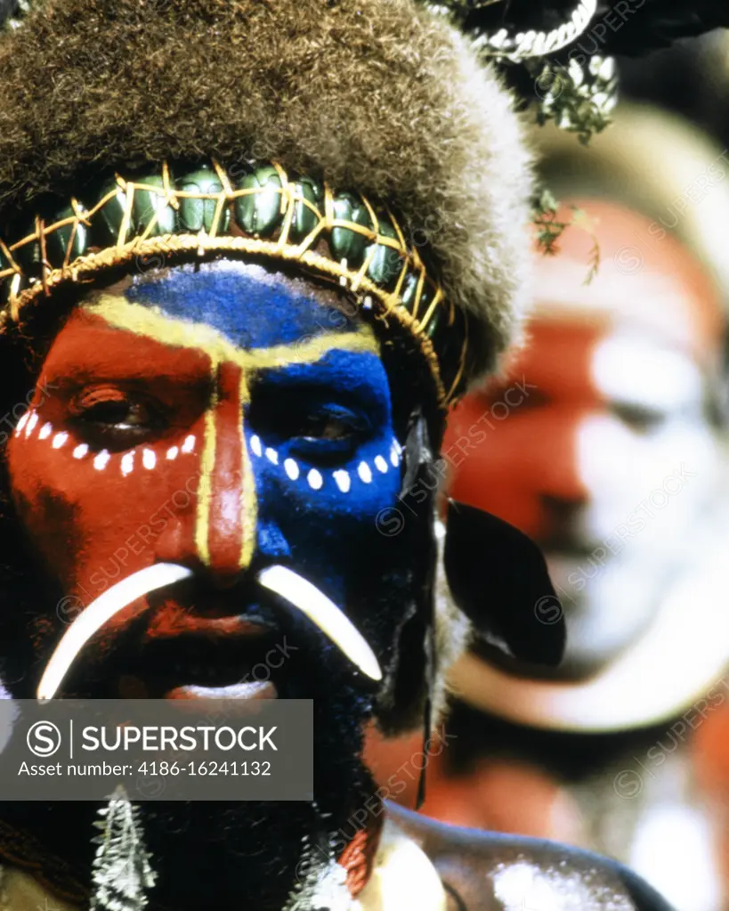 1990s NATIVE INDIGENOUS TRIBAL MAN WITH FACE PAINTED BONE THROUGH NOSE WEARING A HEADDRESS LOOKING AT CAMERA PAPUA NEW GUINEA