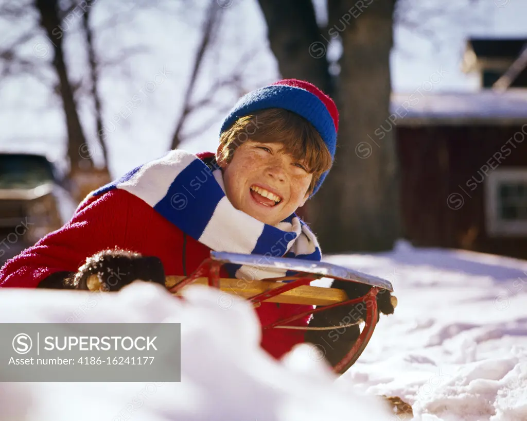 1960s 1970s SMILING BOY ON SLED SLEDDING ON WINTER SNOW 