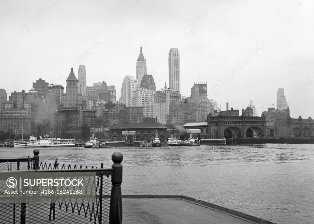 1930s SKYLINE OF LOWER MANHATTAN BUSINESS DISTRICT SIGHT SEEING BOATS TERMINAL SLIPS FROM DECK OF STATEN ISLAND FERRY NYC USA 