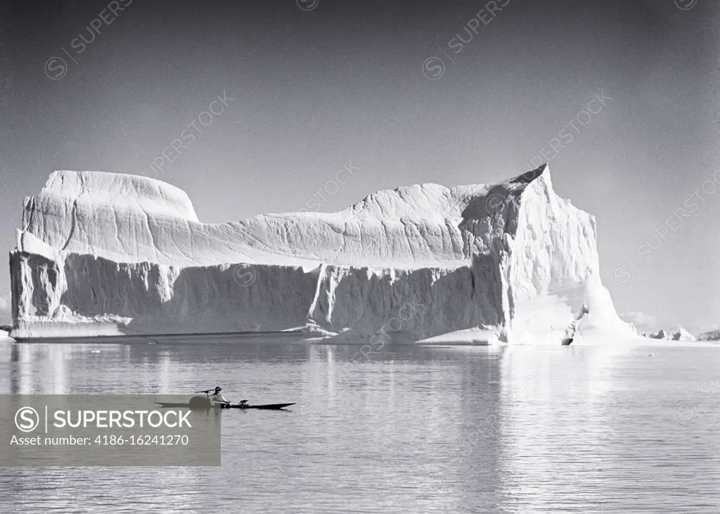 1950s NATIVE AMERICAN INUIT INDIAN MAN IN KAYAK IN FRONT OF AN ICEBERG AT THE SYDKAP SCORESBY SUND GREENLAND