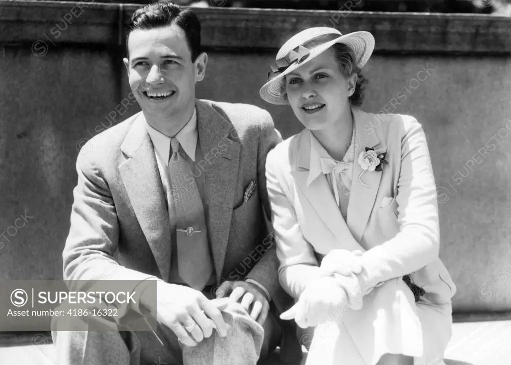 1930S Smiling Couple Sitting Outdoors In The Sunlight