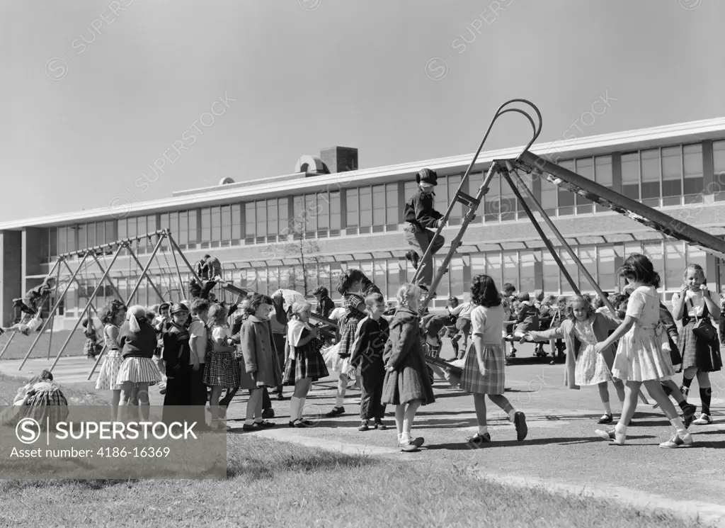 1950S Elementary School Playground At Recess With Children Playing On Slide & Swing Set