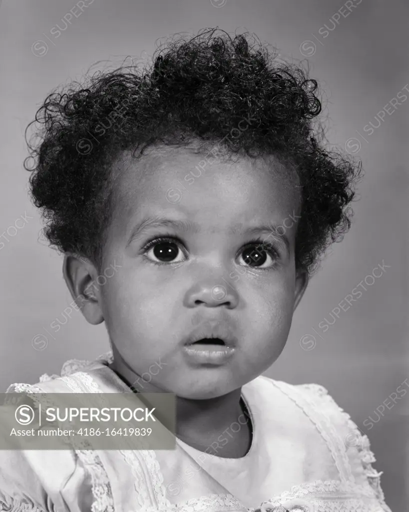 1960s AFRICAN-AMERICAN BABY GIRL LOOKING UP WITH WONDER AMAZEMENT