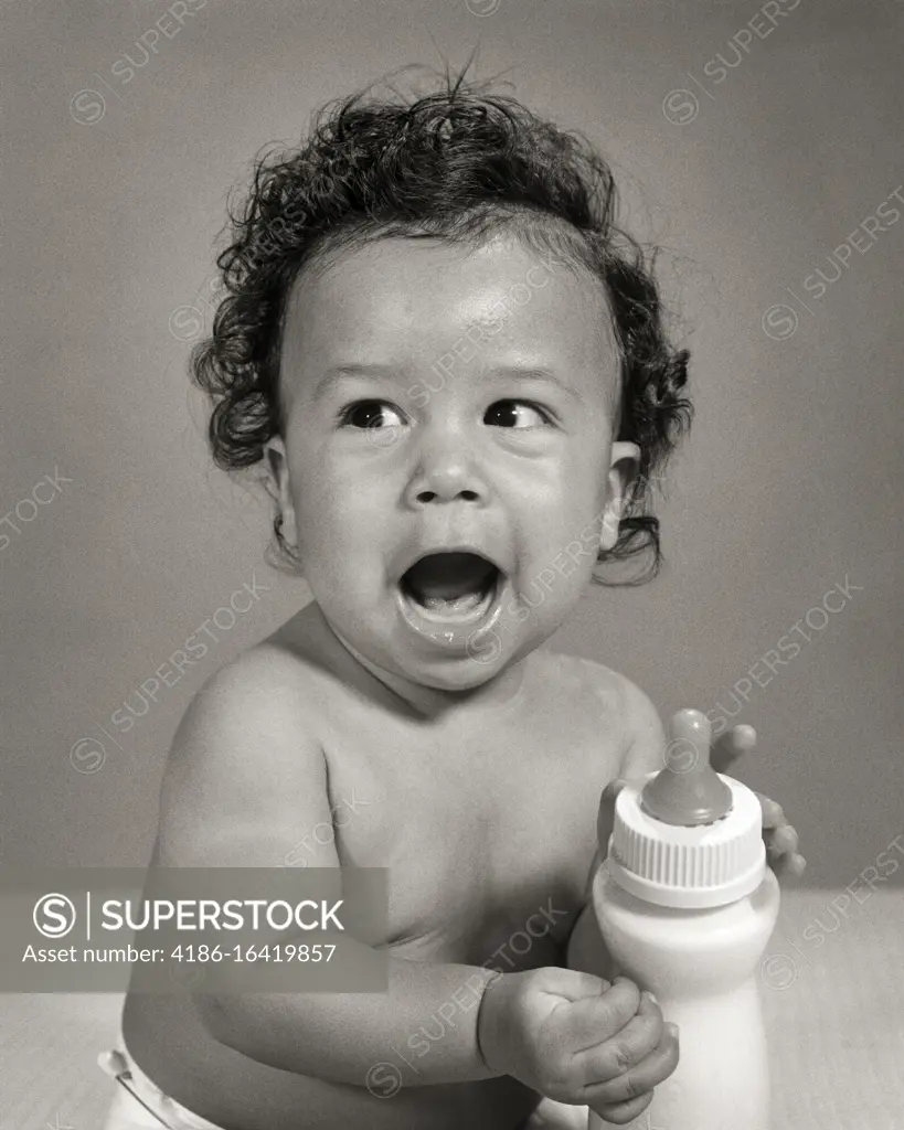 1960s SINGLE VOCALIZING AFRICAN-AMERICAN BABY BOY TODDLER SITTING HOLDING HIS OWN MILK BOTTLE 