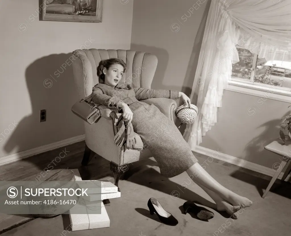 1950S Exhausted Female Slumped In Chair With Shoes Off After Shopping