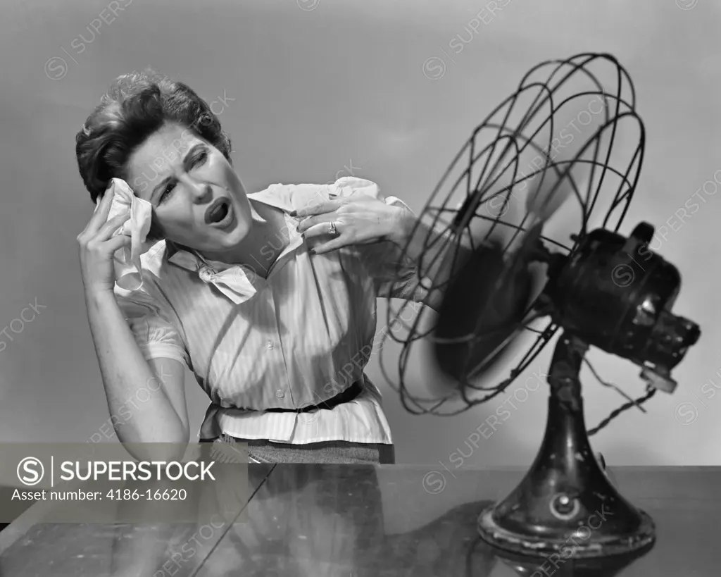 1950S Woman Sitting In Front Of Fan Wiping Forehead Very Hot