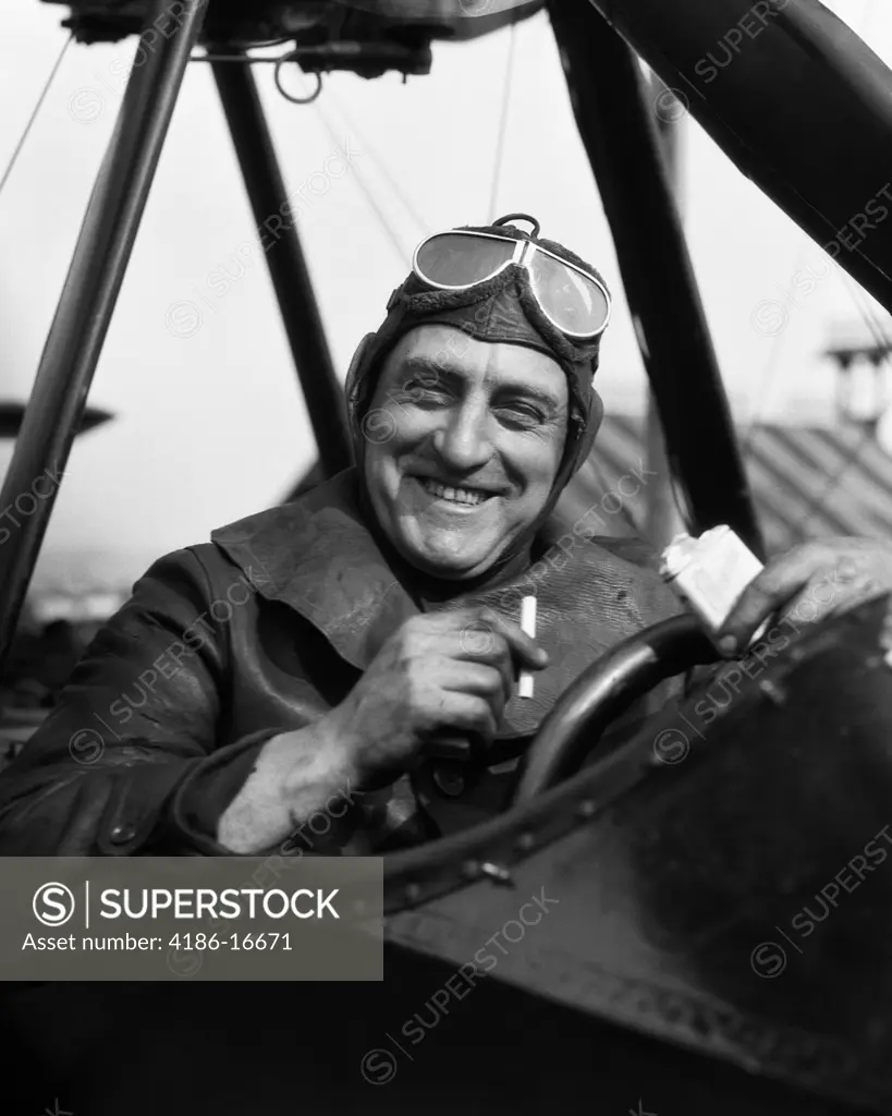 1920S 1930S Pilot Smiling Man In Cockpit Of Airplane Taking Cigarette Out Of Pack