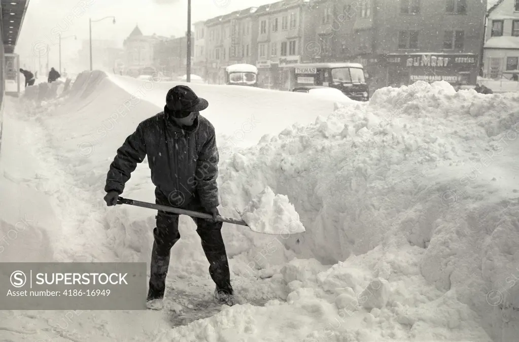 1940S Bundled Up Man With Snow Shovel Shoveling City Side Walk During Winter Storm