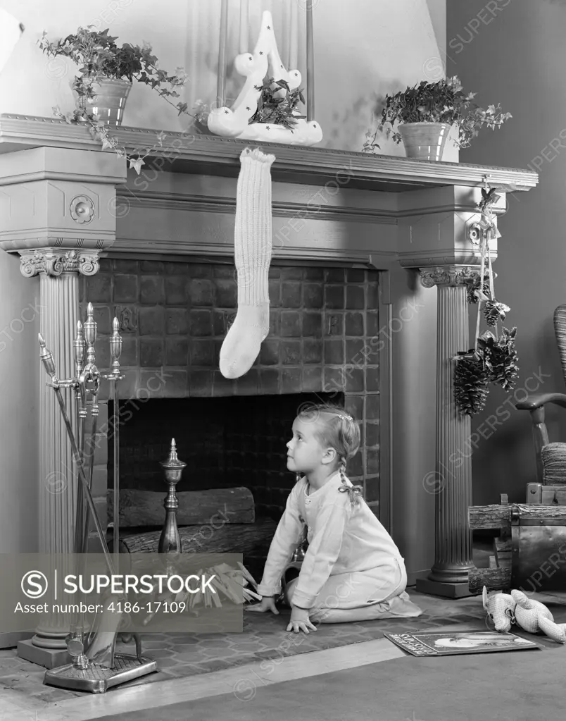 1940S Little Girl In Pajamas Kneeling By Fireplace Under Stocking Waiting For Santa Claus