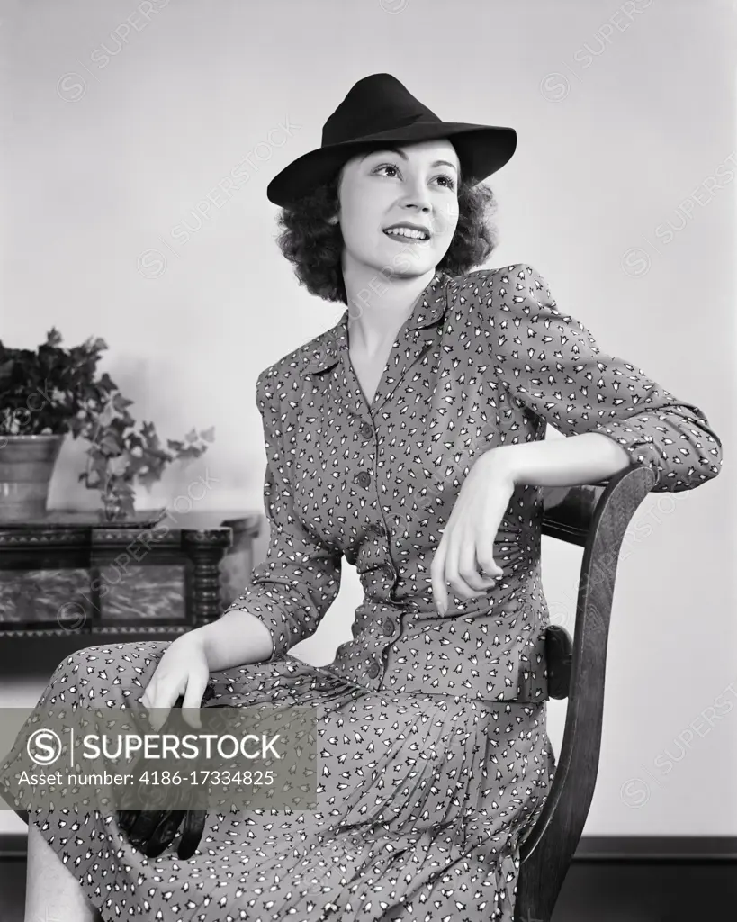 1930s 1940s ATTRACTIVE YOUNG WOMAN PROFESSIONALLY BUSINESS DRESSED IN SUIT WEARING MANNISH HAT SEATED HOLDING PAIR OF GLOVES 