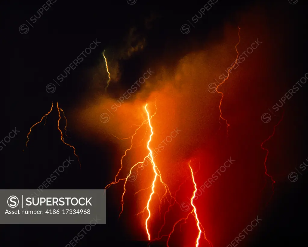 1980s RED AND YELLOW POWERFUL LIGHTNING BOLTS STRIKING FROM DARK CLOUDS AT NIGHT