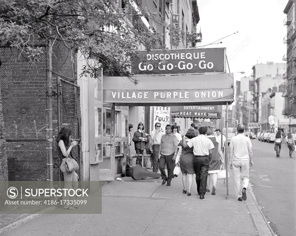 1960s GREENWICH VILLAGE CITY STREET SCENE GROUP OF YOUNG ADULTS WALKING ALONG PAST THE PURPLE ONION A FAMOUS GO-GO BAR NYC USA