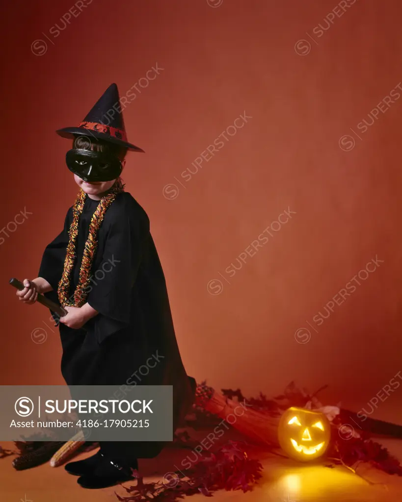 1960s GIRL DRESSED HALLOWEEN COSTUME A WITCH WITH MASK RIDING A BROOM PUMPKIN JACK-O-LANTERN BEHIND HER 