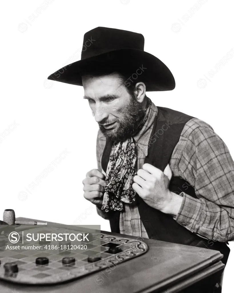 1930s THOUGHTFUL MAN COWBOY PLAYING CHECKERS GAME ON CHECKERBOARD STUDYING DECIDING ON HIS NEXT MOVE