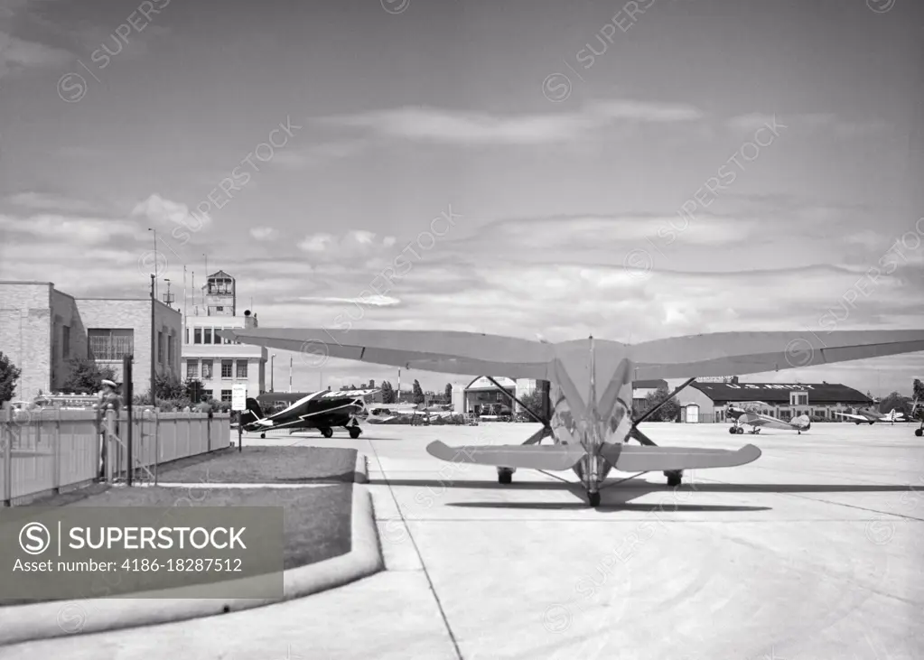 1930s REAR VIEW OF STINSON GULLWING AIRPLANE SITTING ON TARMAC BOSTON AIRPORT NOW LOGAN AIRPORT IN EAST BOSTON MA USA