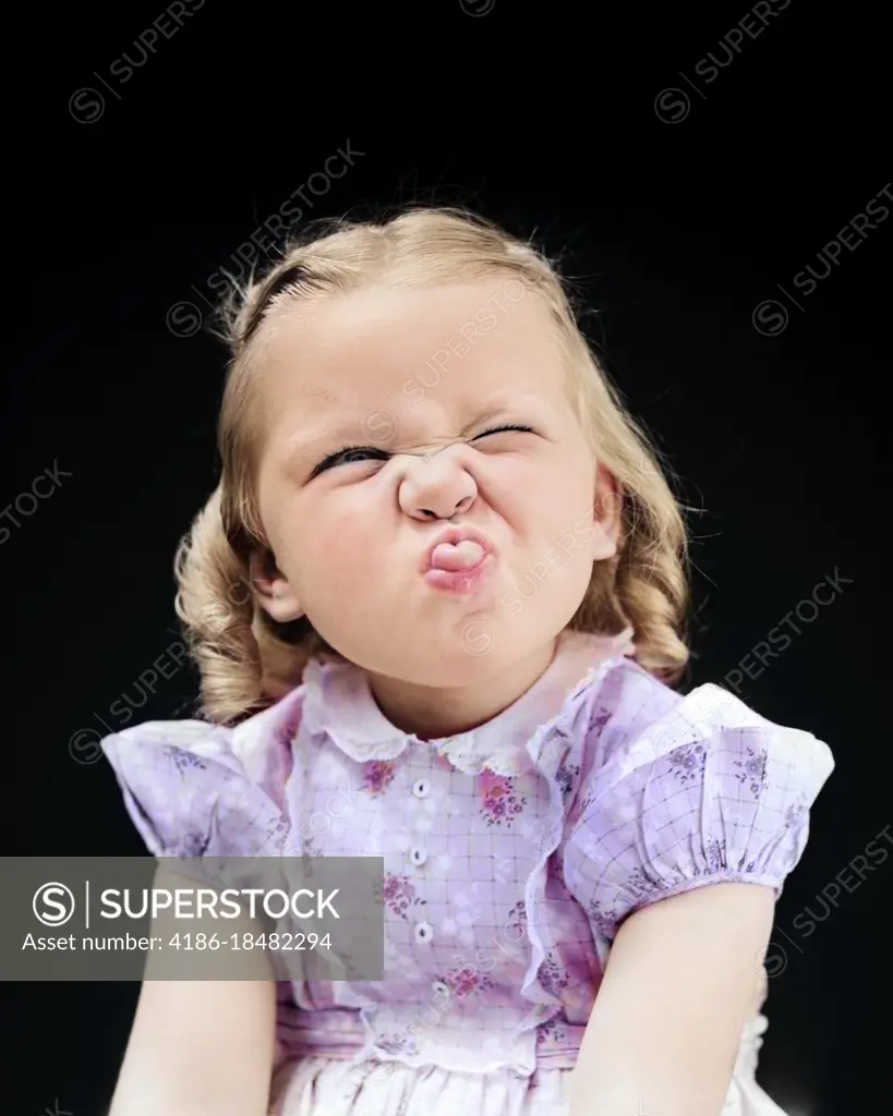 1940s PORTRAIT OF GIRL STICKING OUT TONGUE WRINKLED UP NOSE