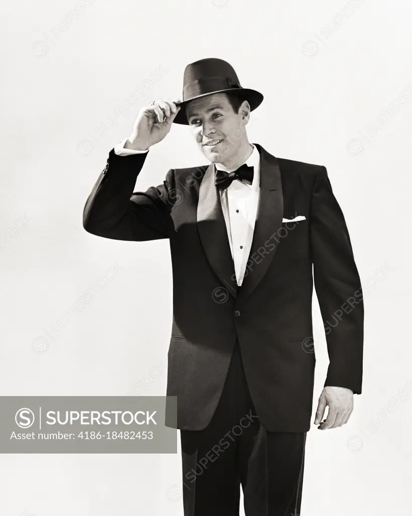 1950s MAN DRESSED IN TUXEDO TIPPING HIS HAT IN GREETING 