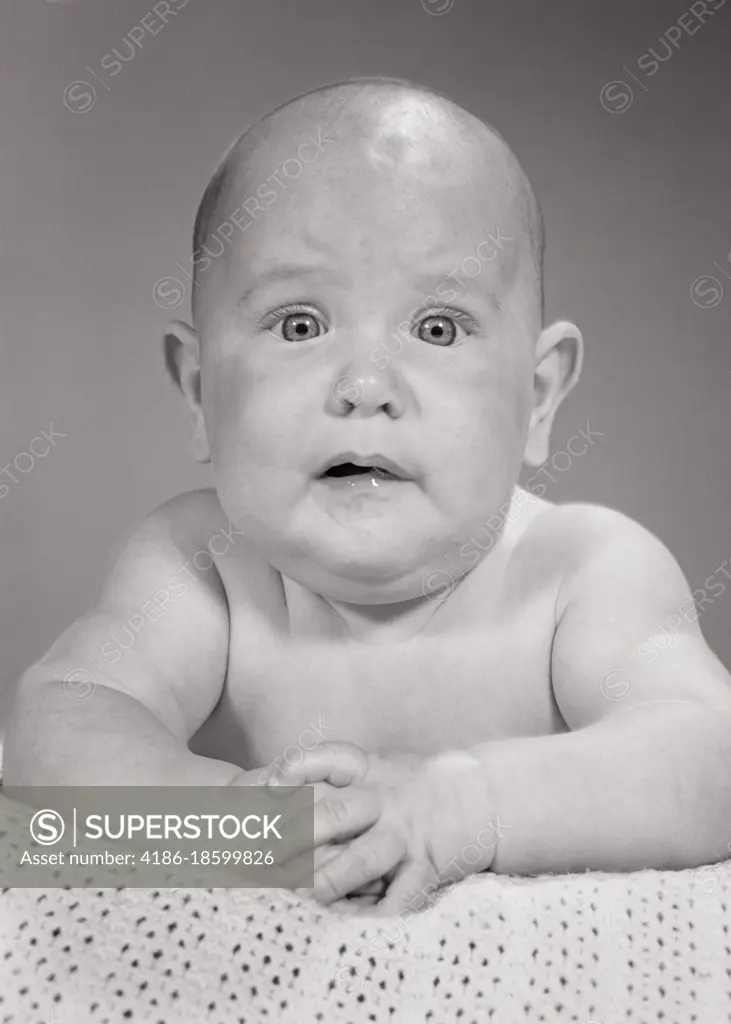 1960s BALD BABY BOY LOOKING AT CAMERA WITH A FUNNY YET SERIOUS WORRIED FACIAL EXPRESSION