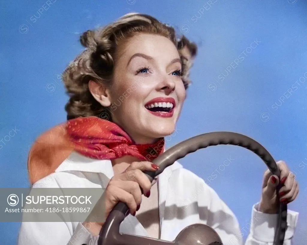 1950s SMILING WOMAN WITH HANDS ON STEERING WHEEL WITH WIND BLOWING BACK HAIR & SCARF STUDIO OUTDOOR