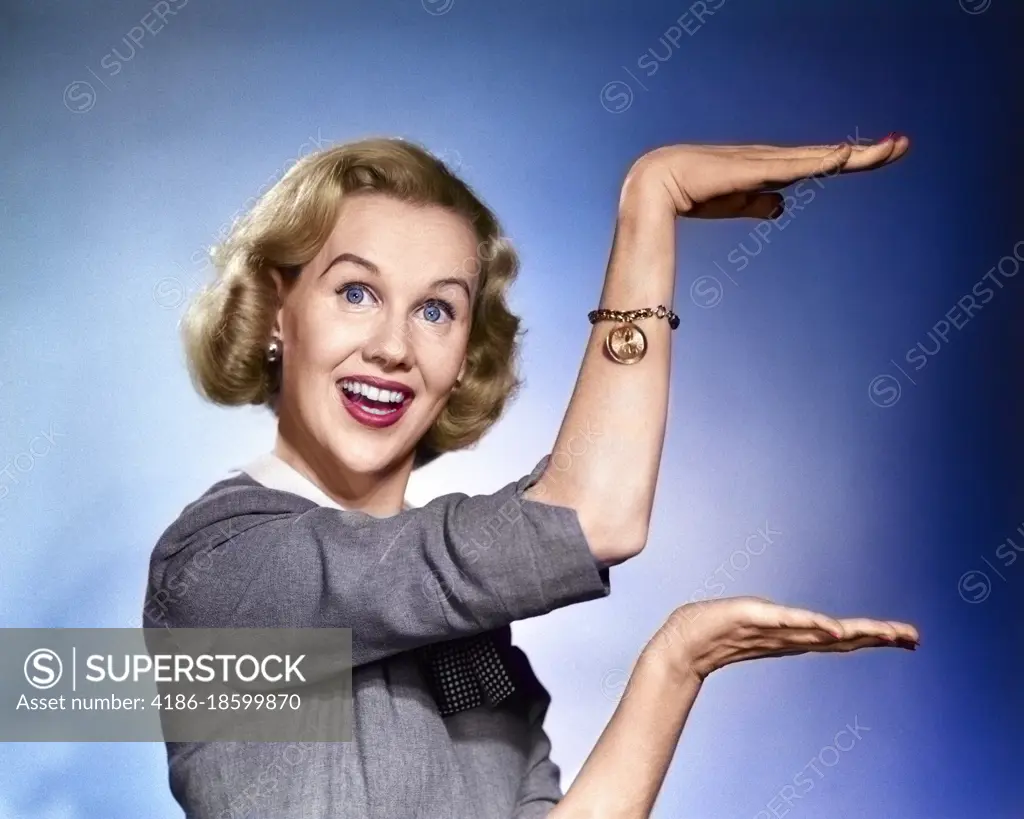 1950s 1960s HAPPY SMILING BLOND WOMAN LOOKING AT CAMERA GESTURING WITH HANDS SHOWING DESCRIBING SIZE OF SOMETHING