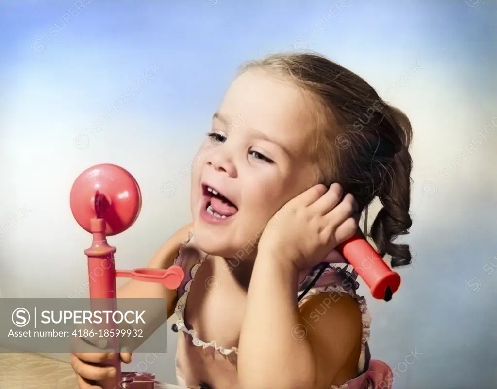 1950s HAPPY LITTLE GIRL TALKING INTO TOY TELEPHONE