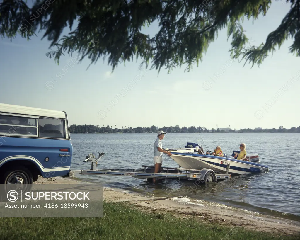 1980s FAMILY VACATION FATHER MOTHER SON LAUNCHING OUTBOARD POWER BOAT ON TRAILER WITH PICKUP TRUCK ONTO FLORIDA LAKE