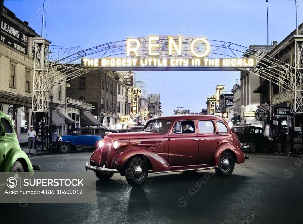 1930s CARS DRIVING AT NIGHT UNDER MAIN STREET NEON ARCH SIGN EXCLAIMING THE BIGGEST LITTLE CITY IN THE WORLD RENO NEVADA USA