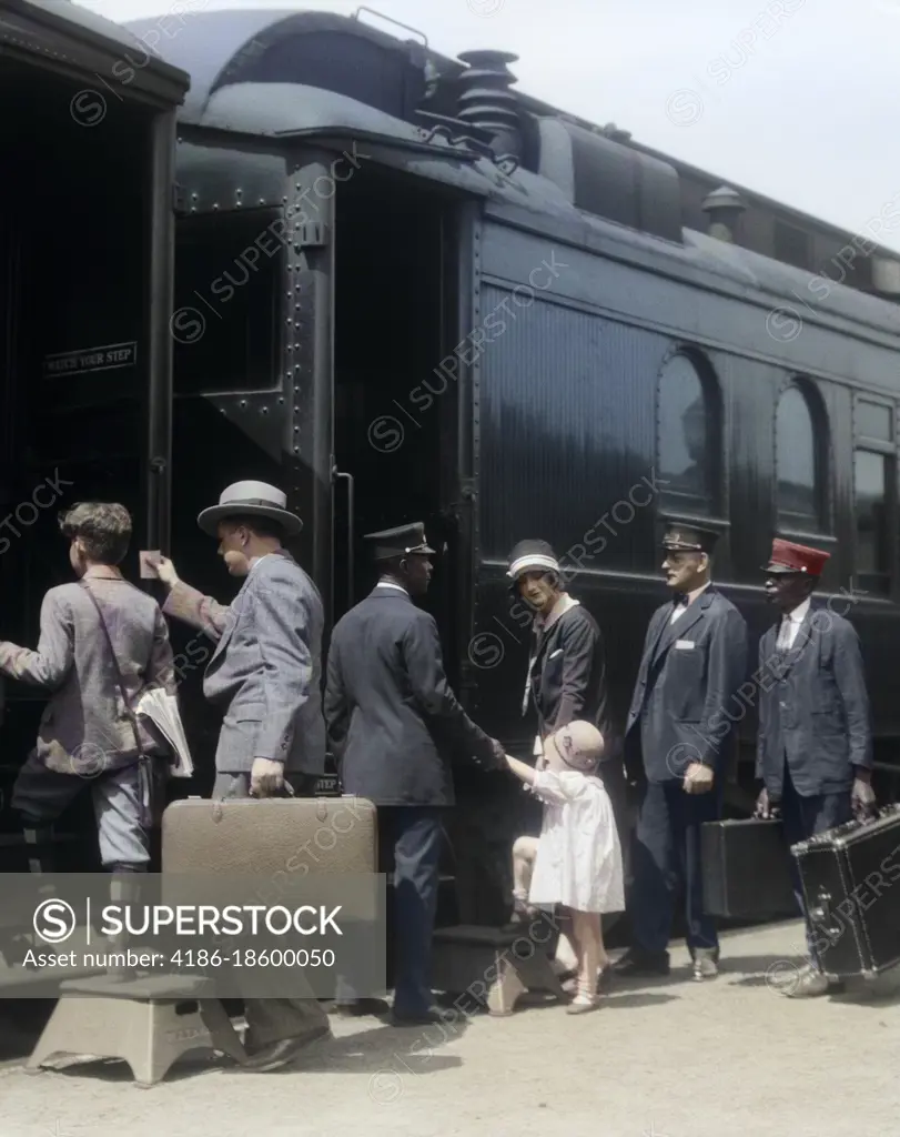 1920s 1930s FAMILY MOTHER FATHER SON DAUGHTER BOARDING PASSENGER TRAIN ASSISTED BY TRAINMAN AND PORTERS CARRYING LUGGAGE OUTDOOR