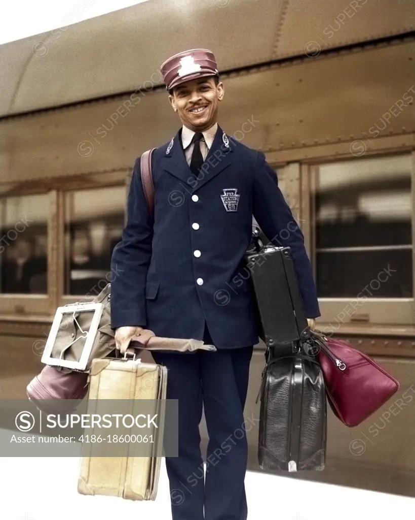 1930s 1940s PORTRAIT SMILING AFRICAN AMERICAN MAN PASSENGER RAILROAD TRAIN RED CAP PORTER LOOKING AT CAMERA CARRYING LUGGAGE