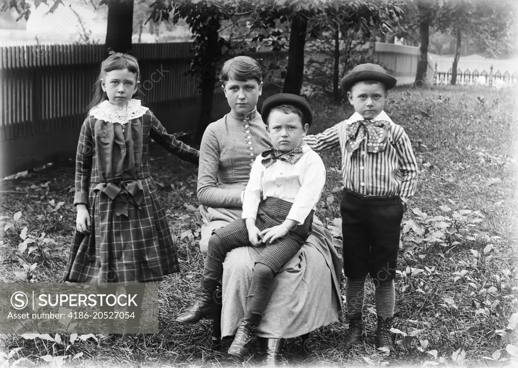 1890s 1900s FAMILY GROUP PORTRAIT SIBLINGS GIRL SISTER TWO BOYS BROTHERS OUTSIDE IN BACKYARD WITH MOTHER LOOKING AT CAMERA