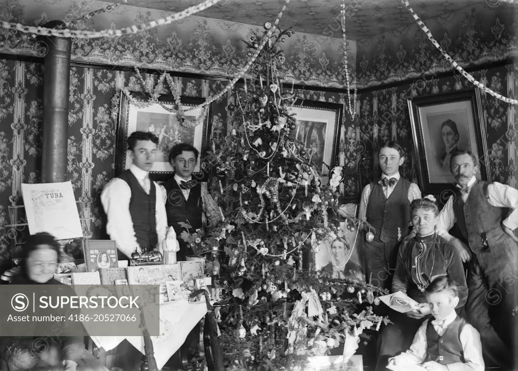 1890 1890s TURN OF CENTURY GROUP PORTRAIT FAMILY THREE GENERATIONS POSING BY CHRISTMAS TREE GIFTS ON TABLE