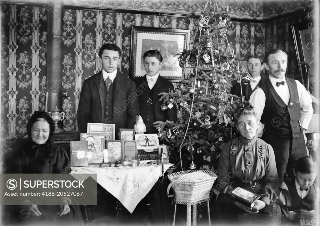 1890 1890s TURN OF CENTURY GROUP PORTRAIT FAMILY THREE GENERATIONS POSING BY CHRISTMAS TREE GIFTS ON TABLE