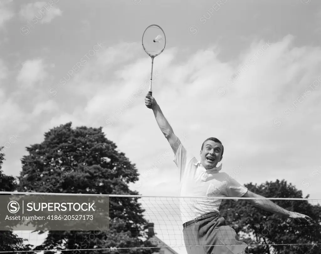 1950s 1960s MAN PLAYING BADMINTON JUMPING UP ARM EXTENDED RACQUET ABOUT TO HIT SHUTTLECOCK BIRDIE WACKY FUNNY EXTREME EFFORT LOB